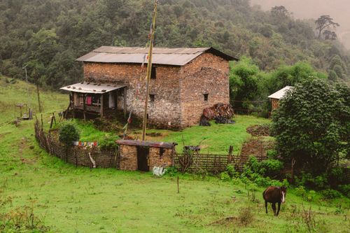 Free Charming stone house with farmyard in verdant mountain scenery, exuding rustic tranquility. Stock Photo
