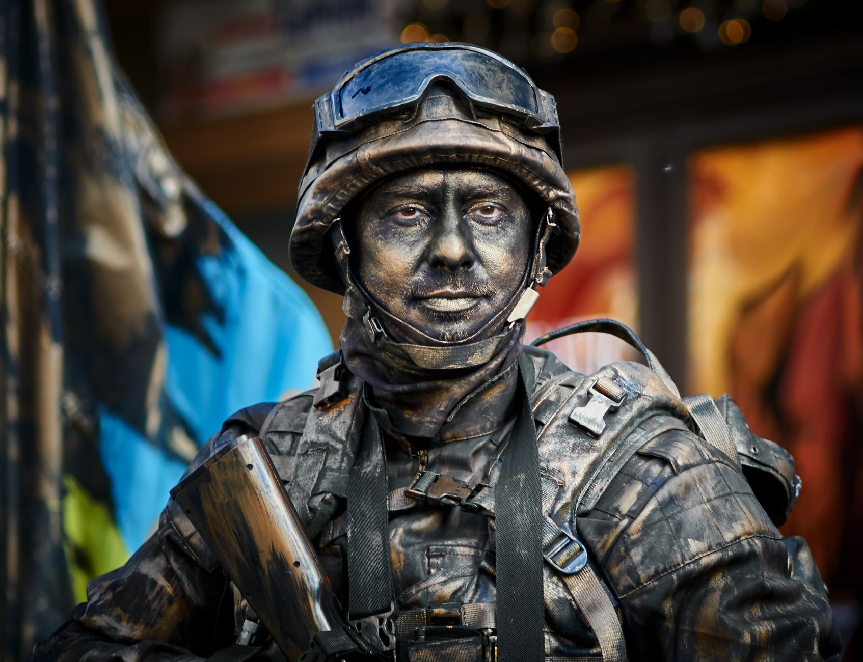 Close-up portrait of a soldier in camouflage gear with face paint and helmet outdoors.