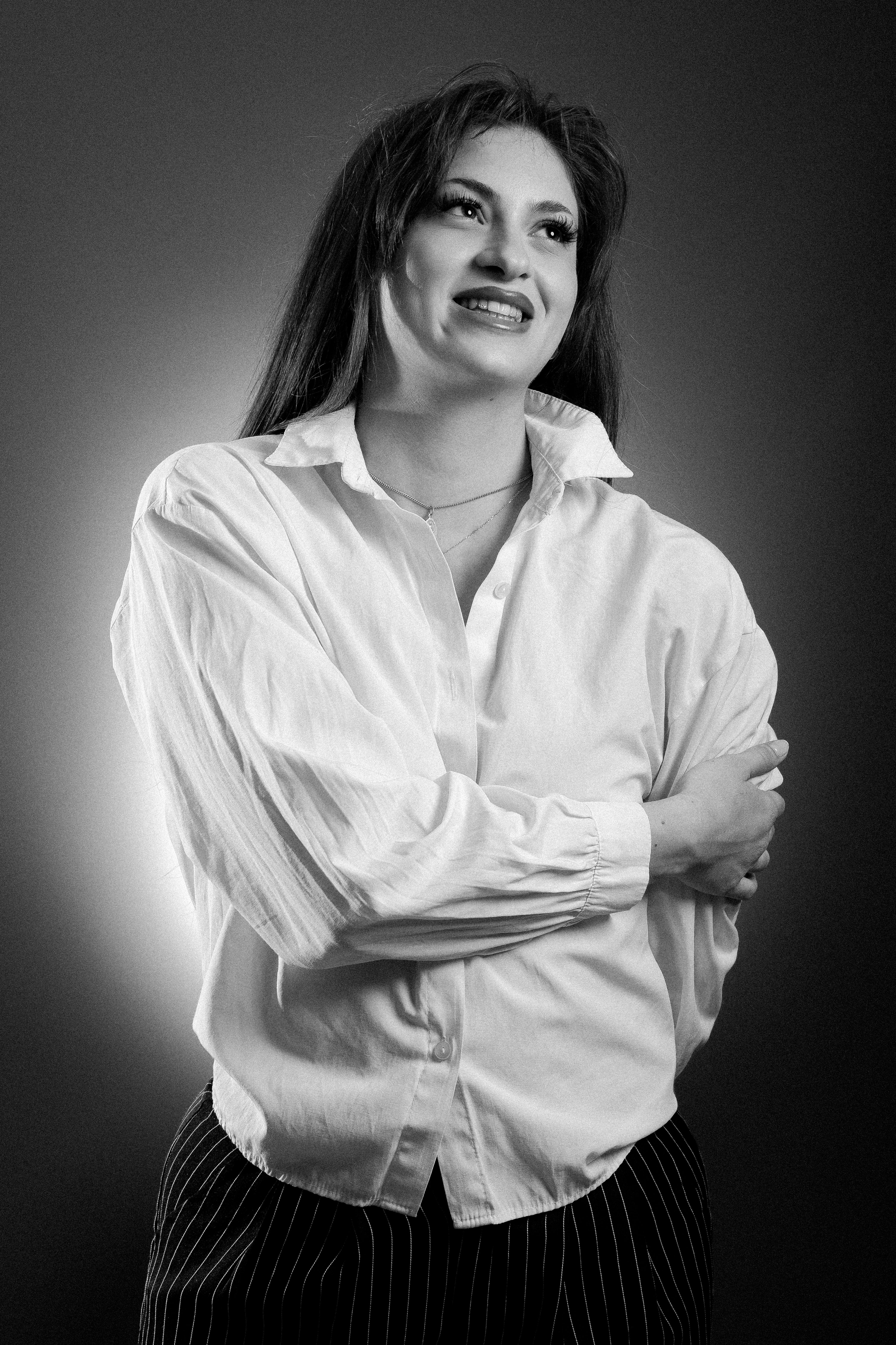 Black and white portrait of a woman smiling in a classic pose with stylish attire.