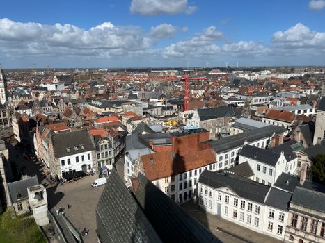 A picturesque aerial view of Ghent's historic cityscape, showcasing charming medieval architecture under a blue sky.