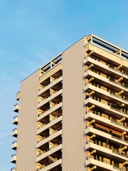 A modern apartment building with geometric design against a clear blue sky, showcasing urban architecture.