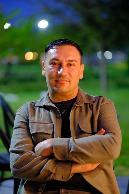 Free Portrait of a man sitting outdoors with arms crossed during twilight. Stock Photo