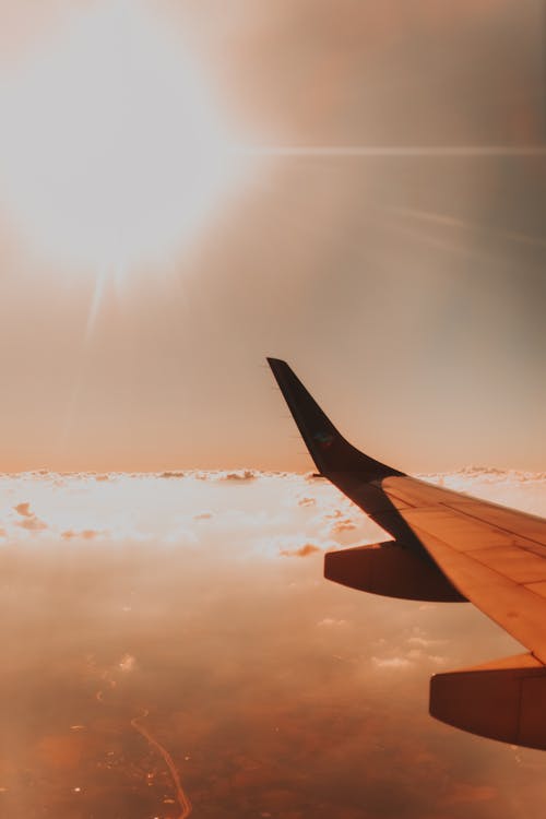 明るい太陽に対して雲の上の飛行機の翼