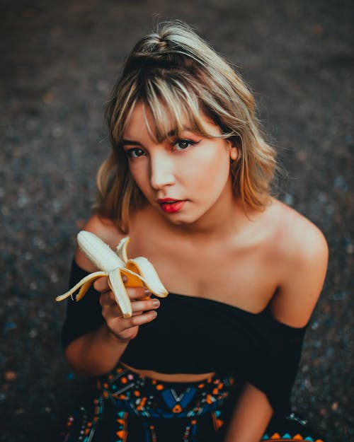 Young dreamy woman with banana on street