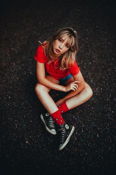 在圣保罗的柏油马路上，一位时尚女士展示着匡威运动鞋和魅力风格