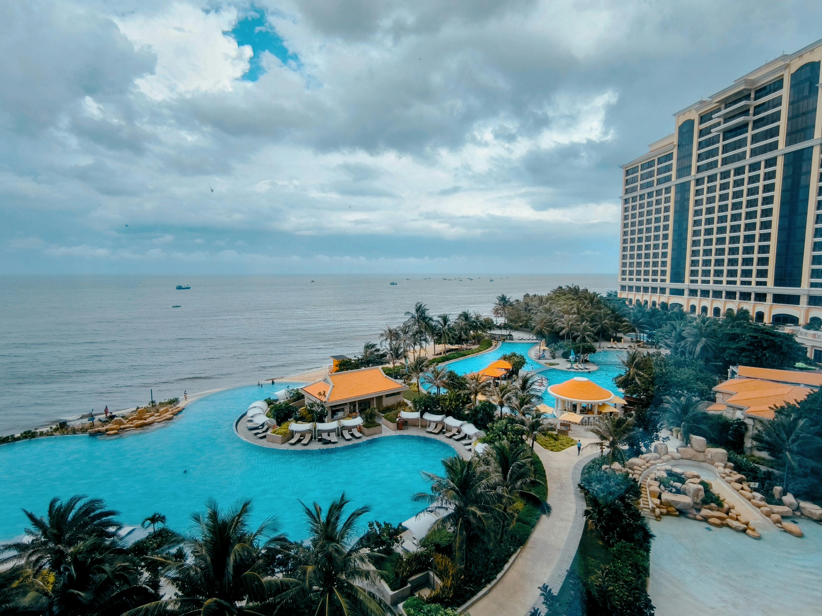 Aerial view of a tropical seaside resort with an expansive infinity pool and luxury amenities.