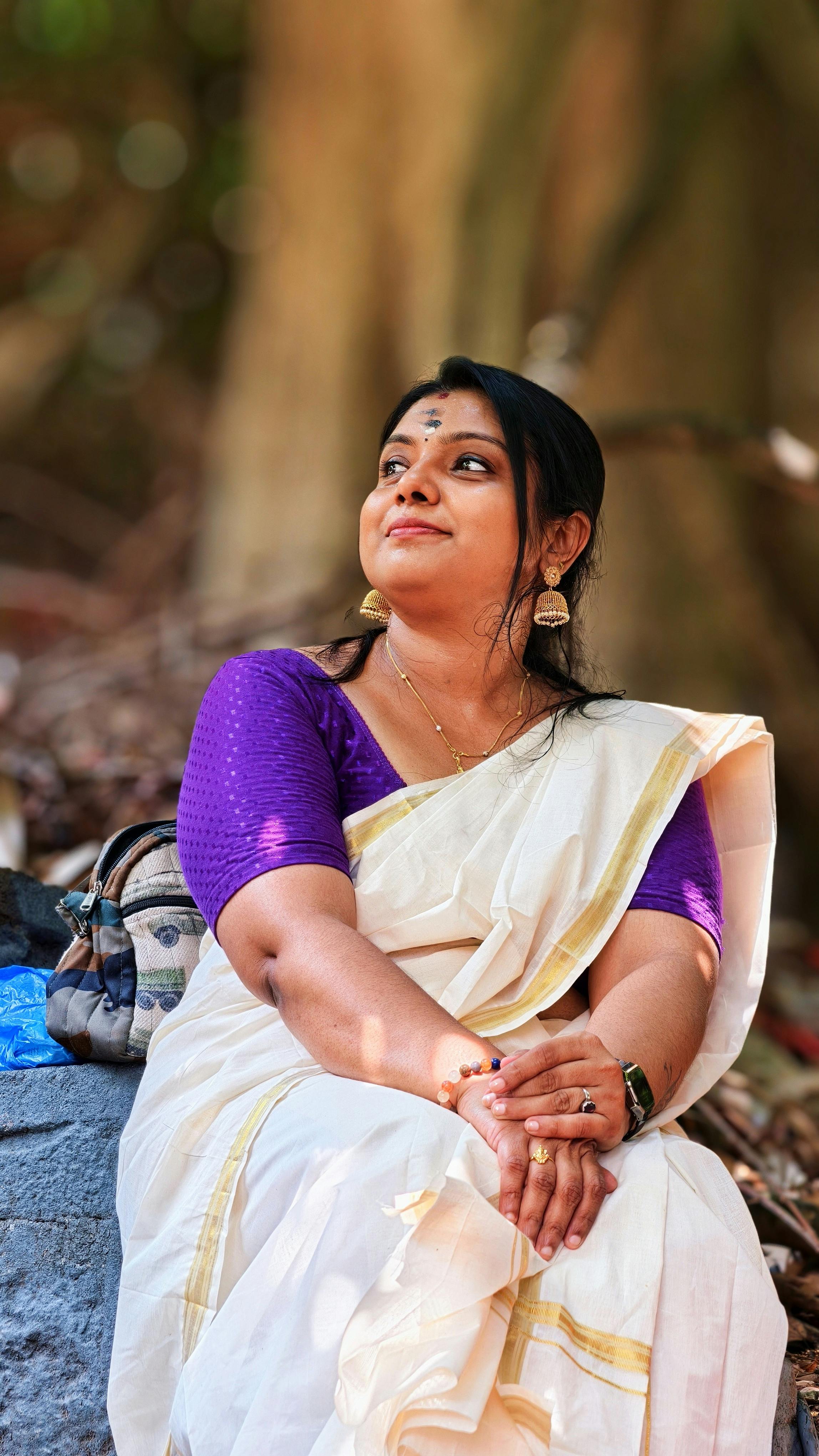 South Asian woman in traditional attire poses gracefully outdoors in Kerala, India.
