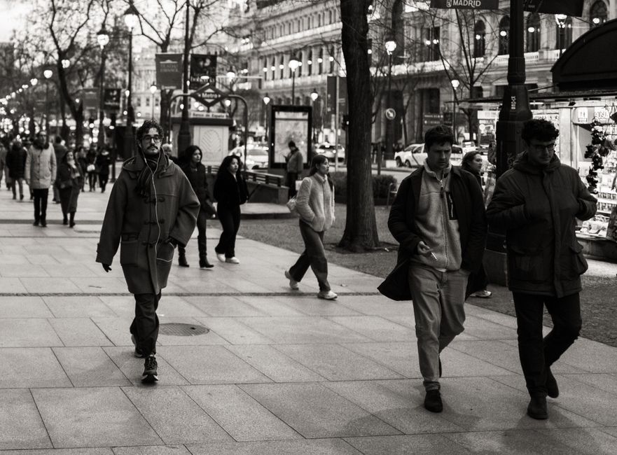 Gente caminando por una calle concurrida de Madrid, capturando la vida urbana y la arquitectura.