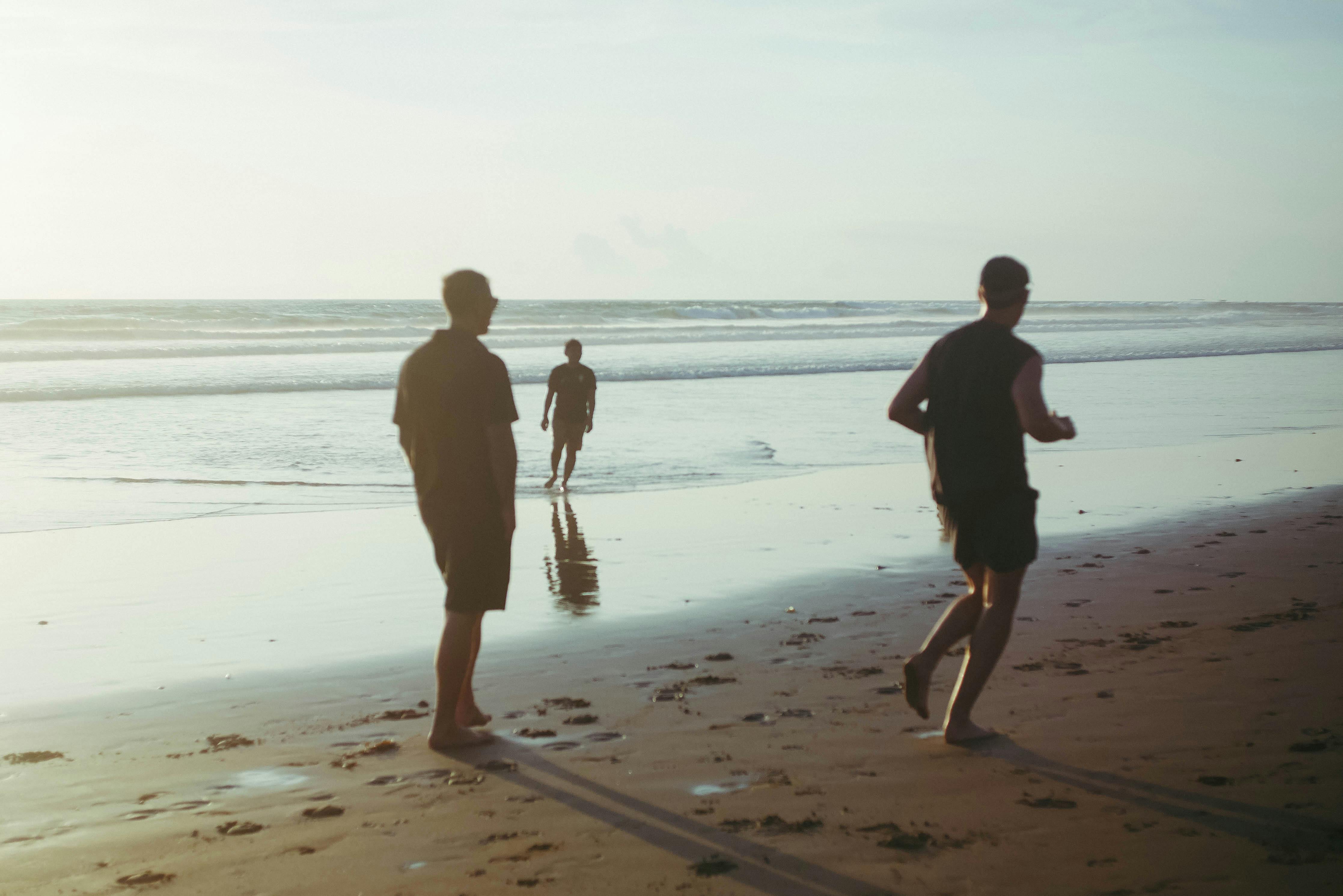 ฟรี ภาพถ่ายแสดงให้เห็นคนสามคนกำลังเดินเล่นอย่างสงบสุขริมชายหาดบาหลีในยามพระอาทิตย์ตกดิน สะท้อนให้เห็นถึงแก่นแท้ของการพักผ่อนหย่อนใจ คลังภาพถ่าย