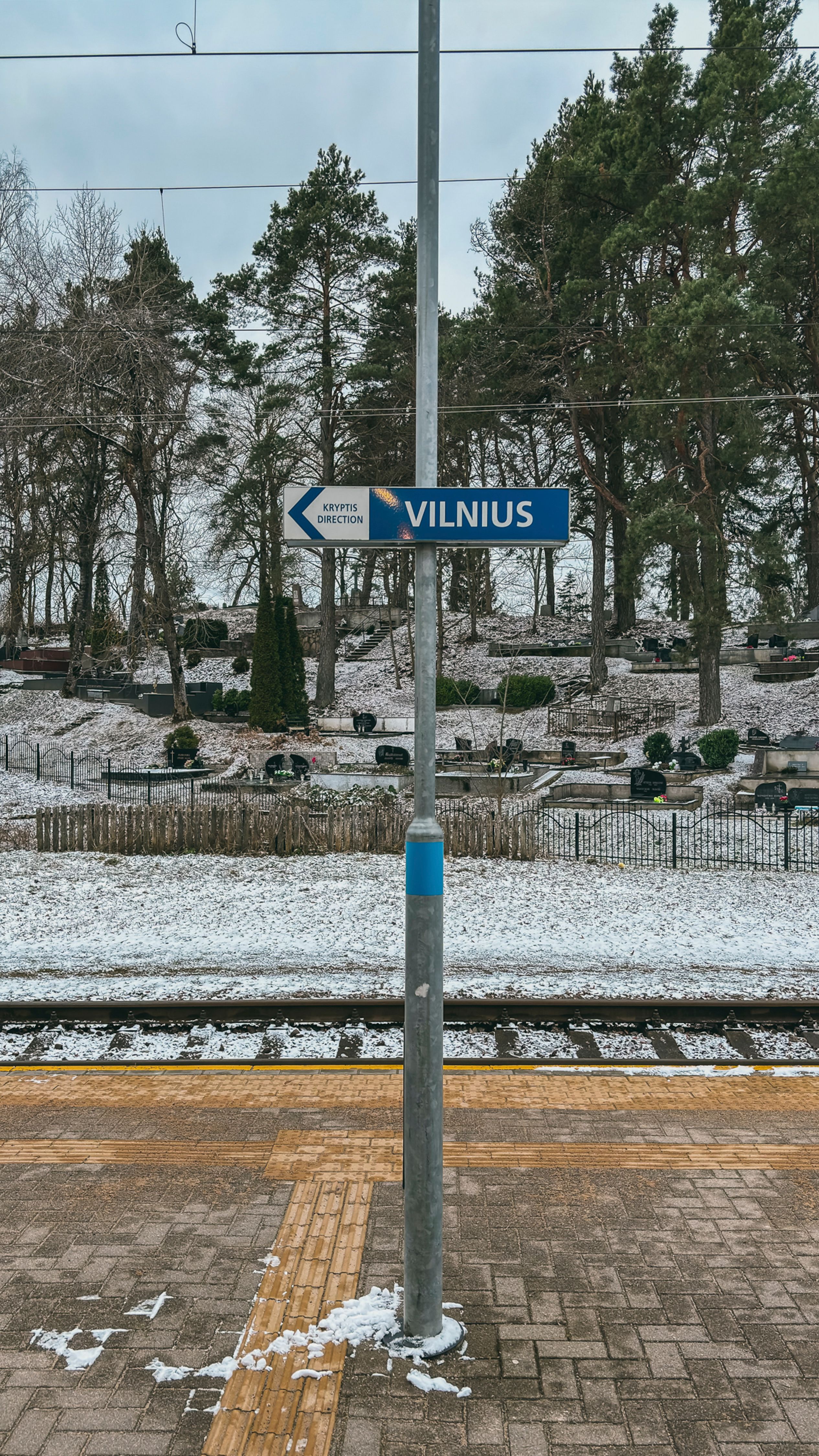 Winter scene at a train station in Vilnius with snowy surroundings and railway tracks.