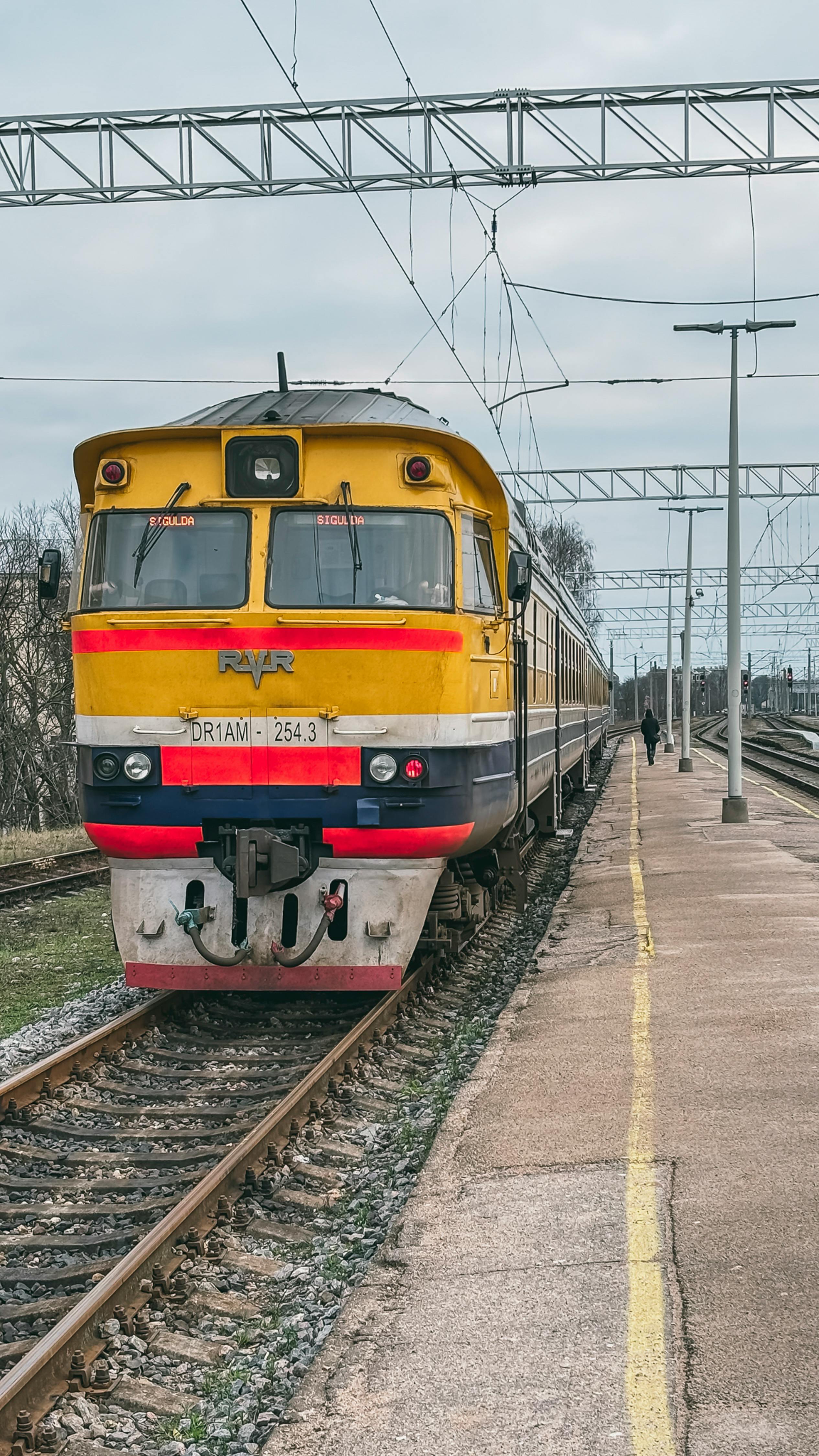 A vibrant train arrives at Sigulda Station, Latvia, offering a classic travel scene.