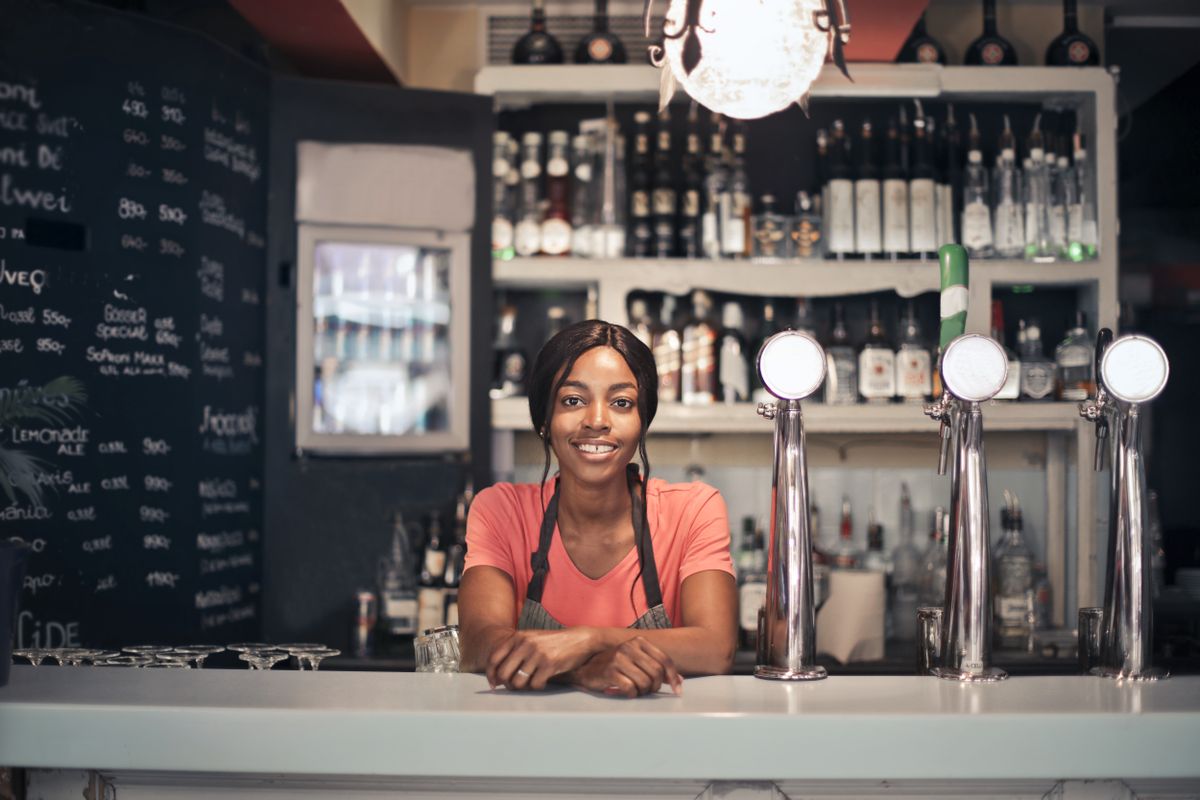 A smiling business owner leaning on her shop counter