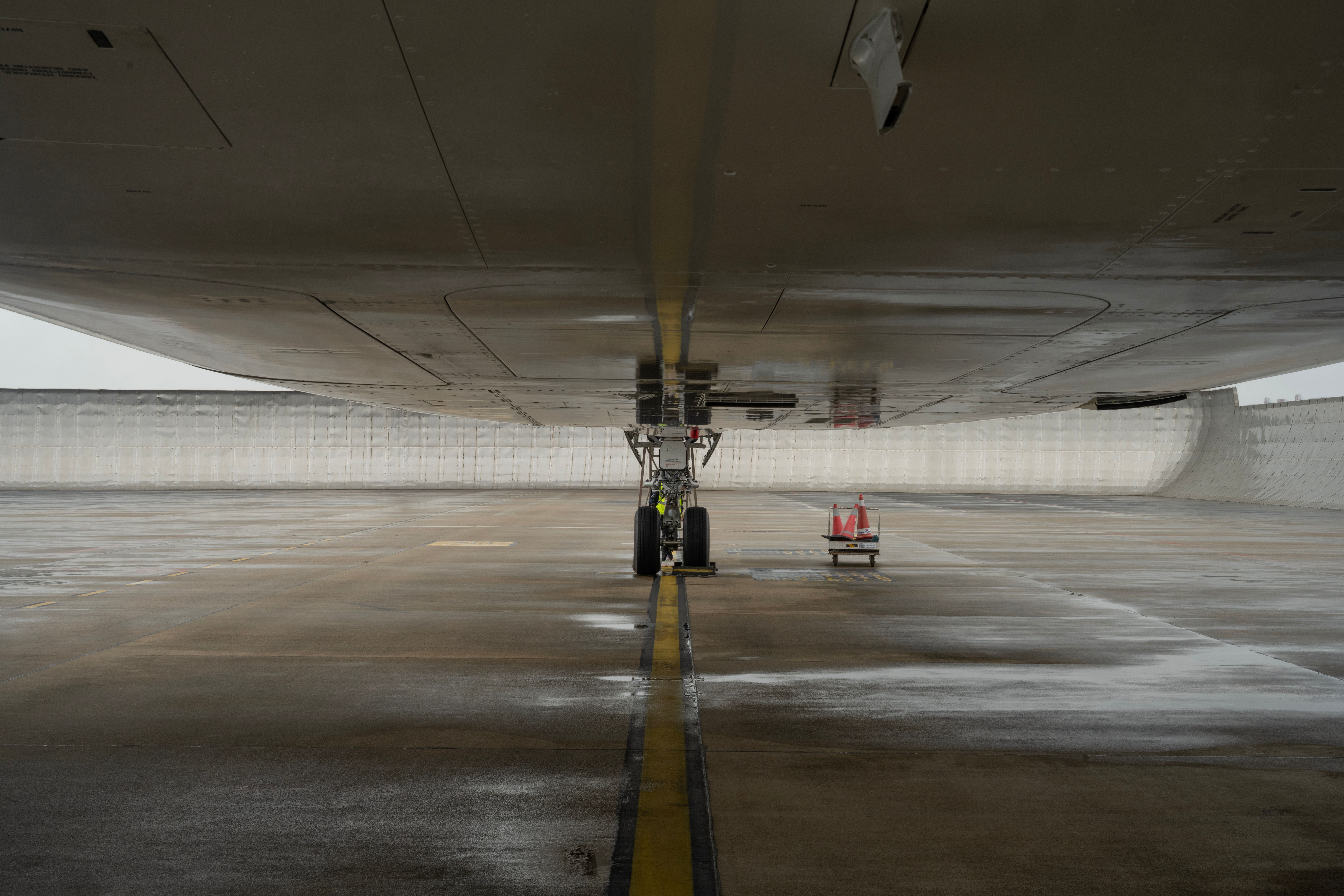 Close-up view of aircraft undercarriage on a wet airport tarmac, highlighting engineering details.