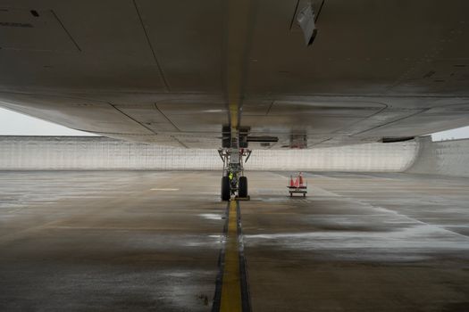 Close-up view of aircraft undercarriage on a wet airport tarmac, highlighting engineering details.
