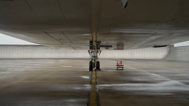 Close-up view of aircraft undercarriage on a wet airport tarmac, highlighting engineering details.