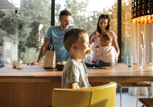 Free Kid eating sweets in kitchen with family Stock Photo