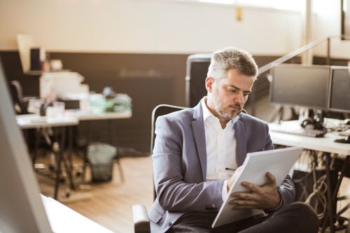 Free Businessman in formal wear writing on a notepad with concentration in a modern office. Stock Photo