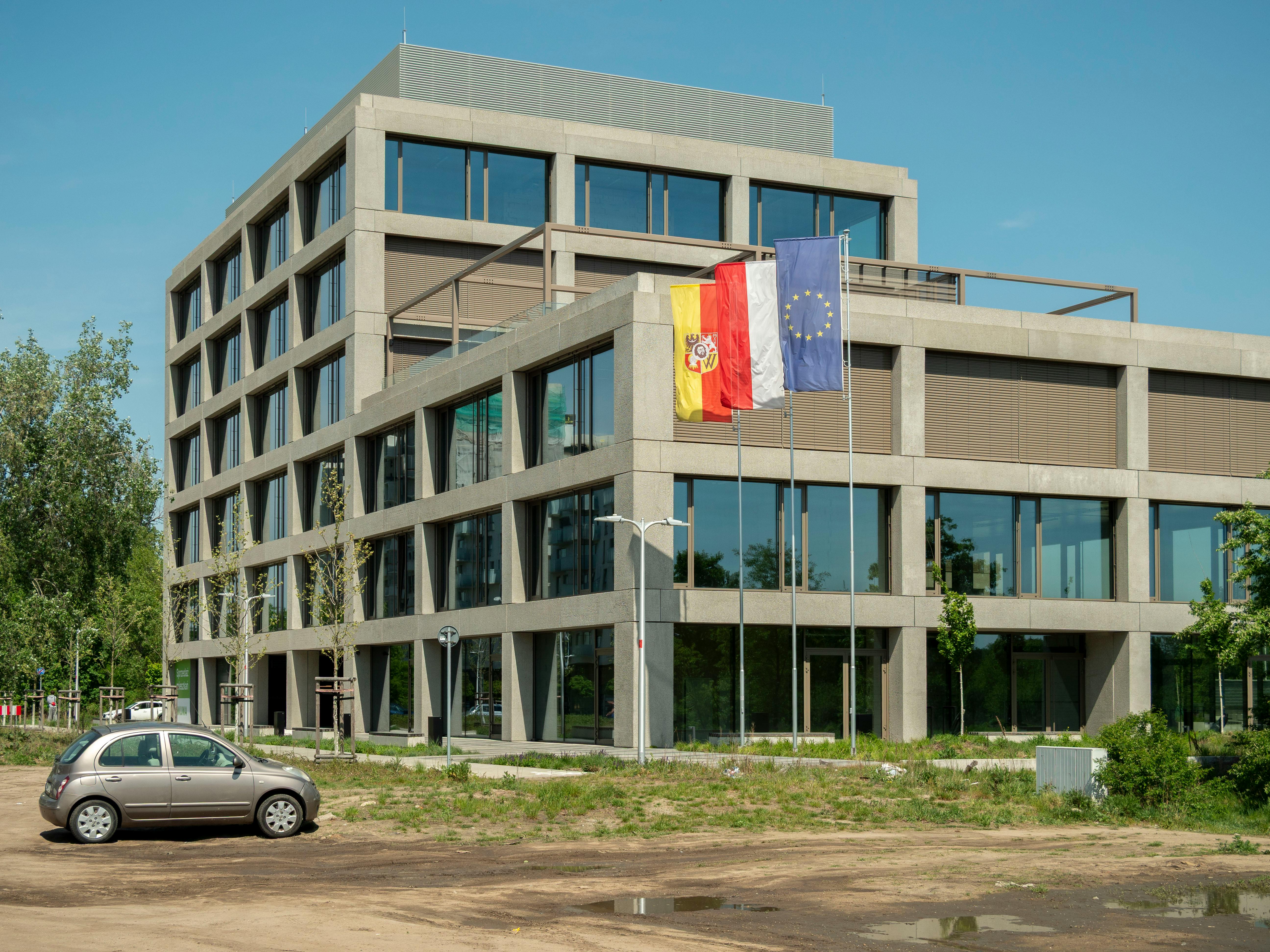 Contemporary office building in Wrocław, featuring European and local flags, under clear sky.