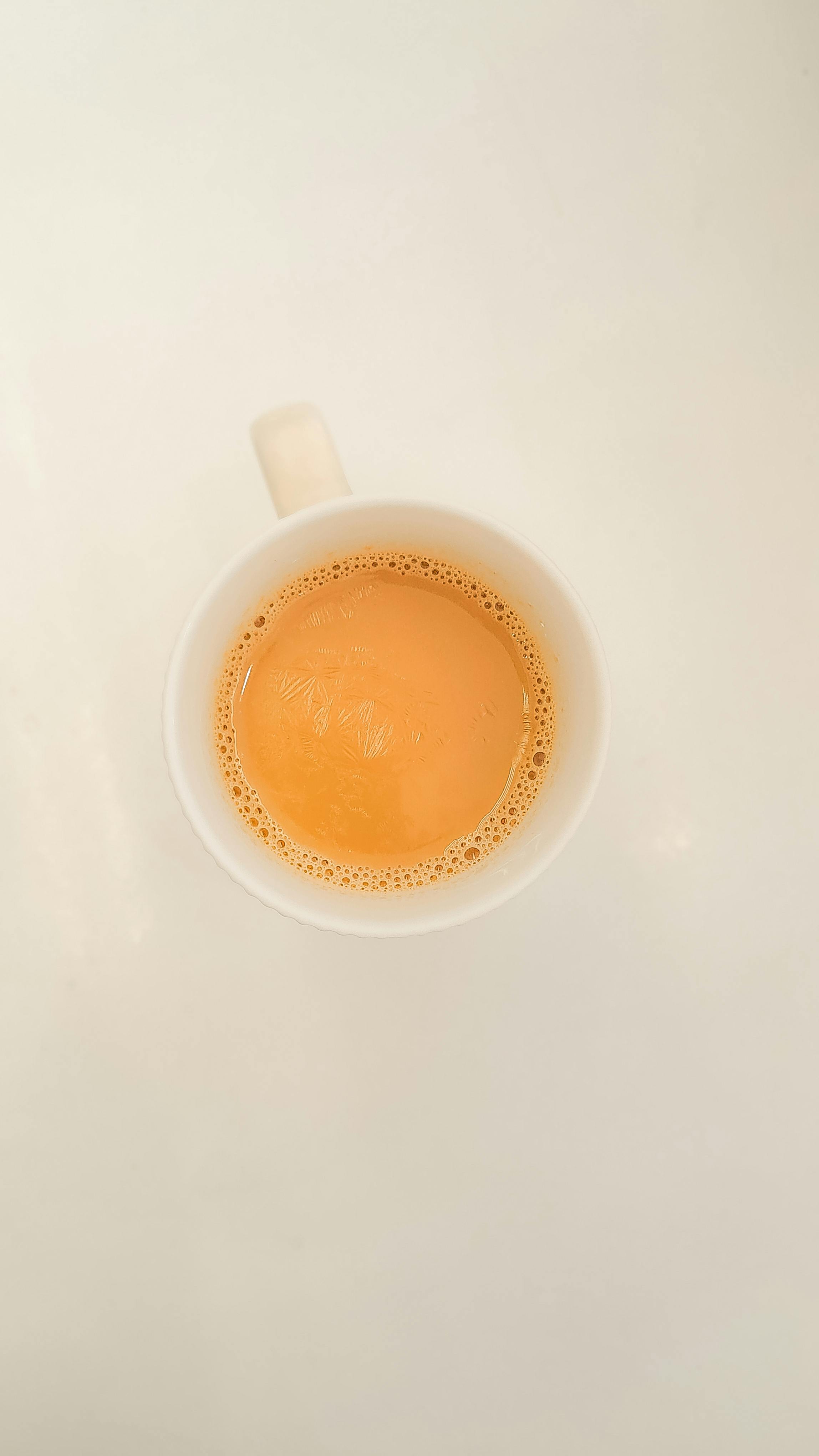 Minimalistic flat lay of a hot cup of tea on a white background.