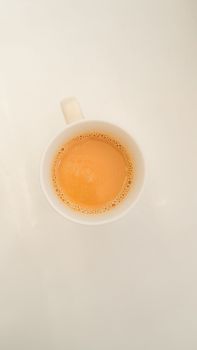 Minimalistic flat lay of a hot cup of tea on a white background.