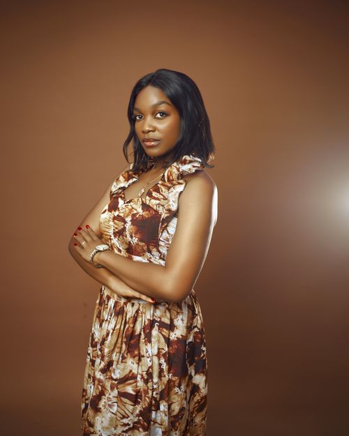 Free Studio portrait of a confident woman in a floral dress on a warm brown backdrop. Stock Photo