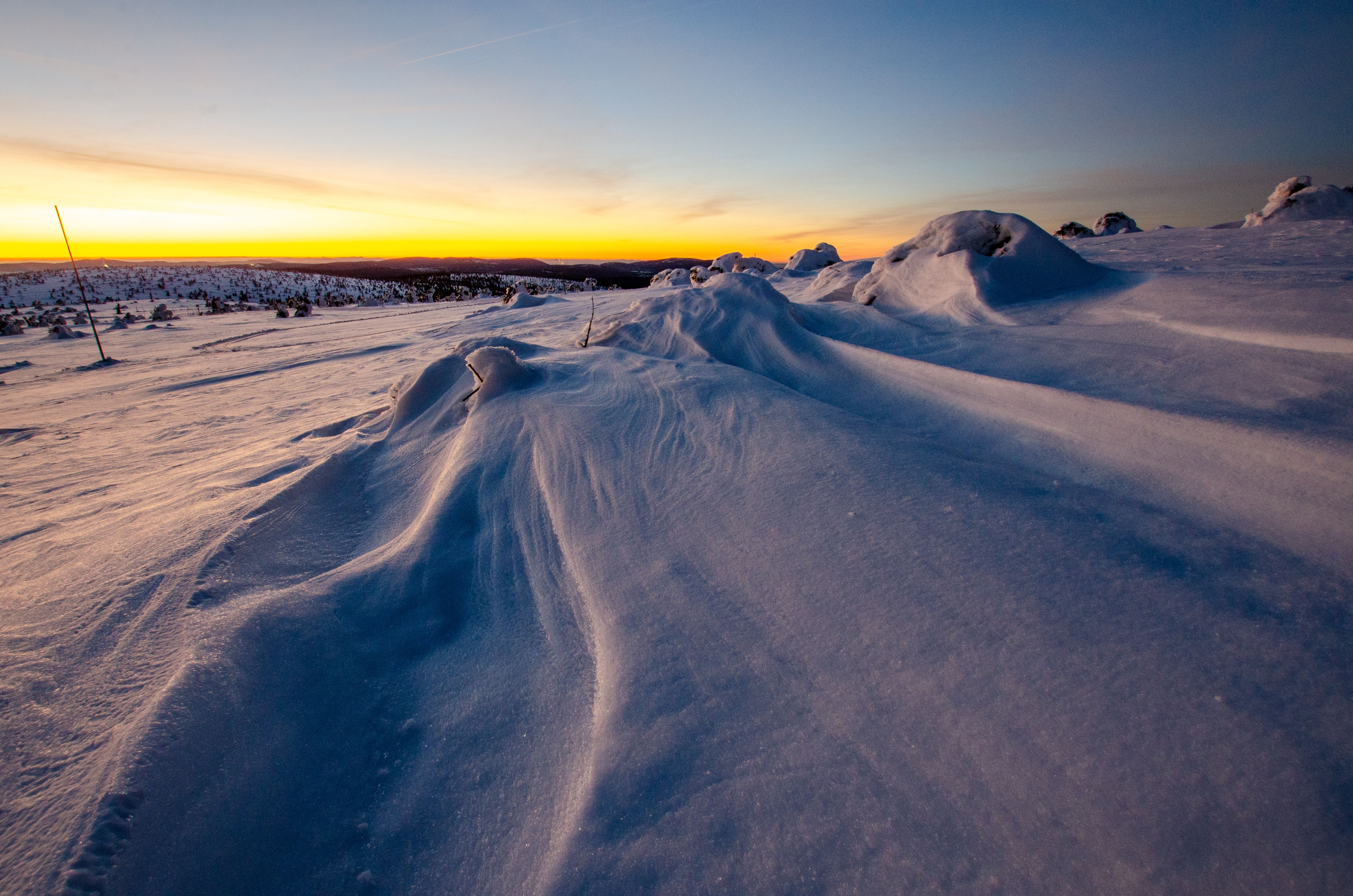 Skiløper i dypsnø med solnedgang i bakgrunnen