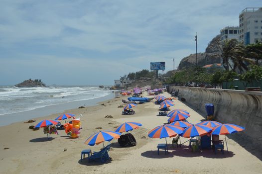 Brightly colored umbrellas line a tropical beach, offering shade on a sunny day.