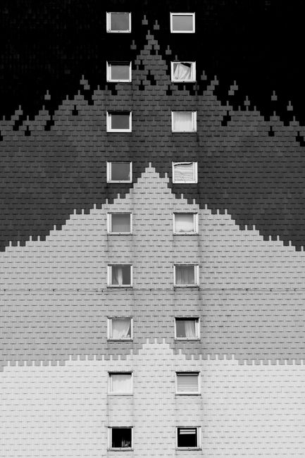 Monochrome abstract building facade featuring repeated windows and geometric patterns.