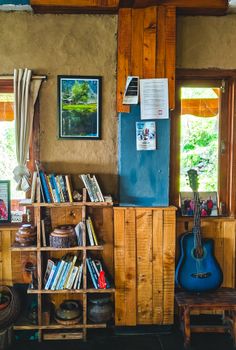 Rustic interior featuring a bookshelf, blue guitar, and framed artwork, embodying a cozy and eclectic vibe.