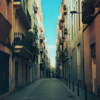 A picturesque view of a narrow street in Barcelona, bathed in warm afternoon sunlight, capturing the city's unique architecture.