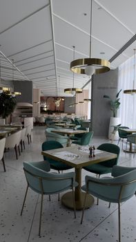 Chic restaurant with modern decor, featuring teal chairs and gold accents, ideal for dining.