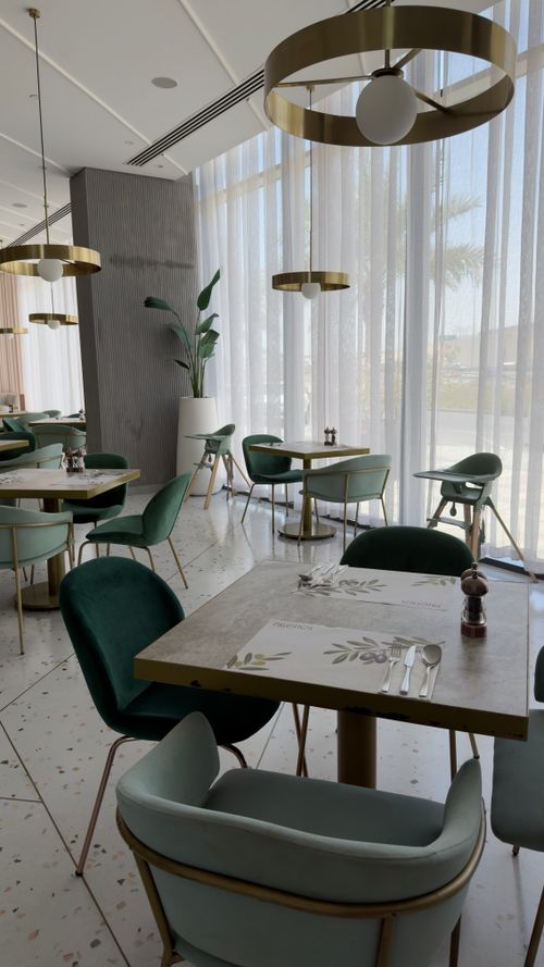 Free Elegant modern cafe interior with green chairs and large windows creating a bright atmosphere. Stock Photo