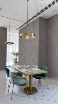 Stylish dining area with gold accents, teal chairs, and modern lighting fixtures for a chic ambiance.