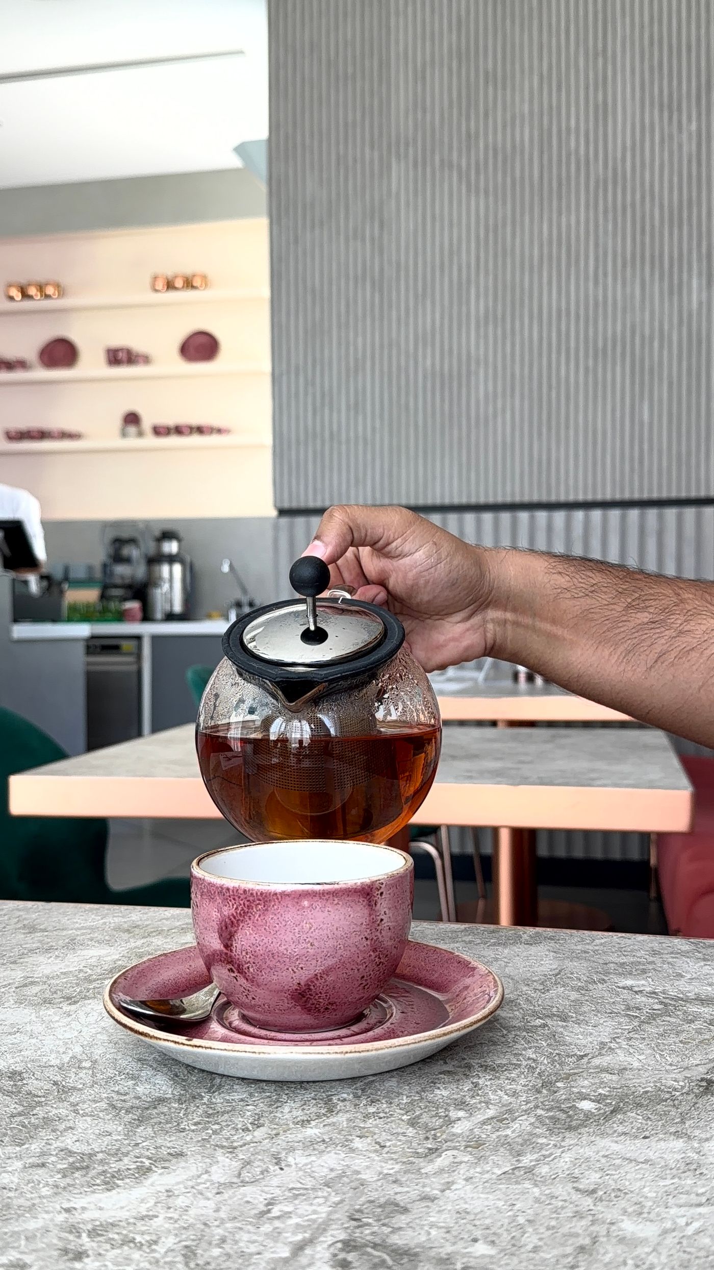 Freshly brewed tea being poured from a teapot into a cup in a modern café