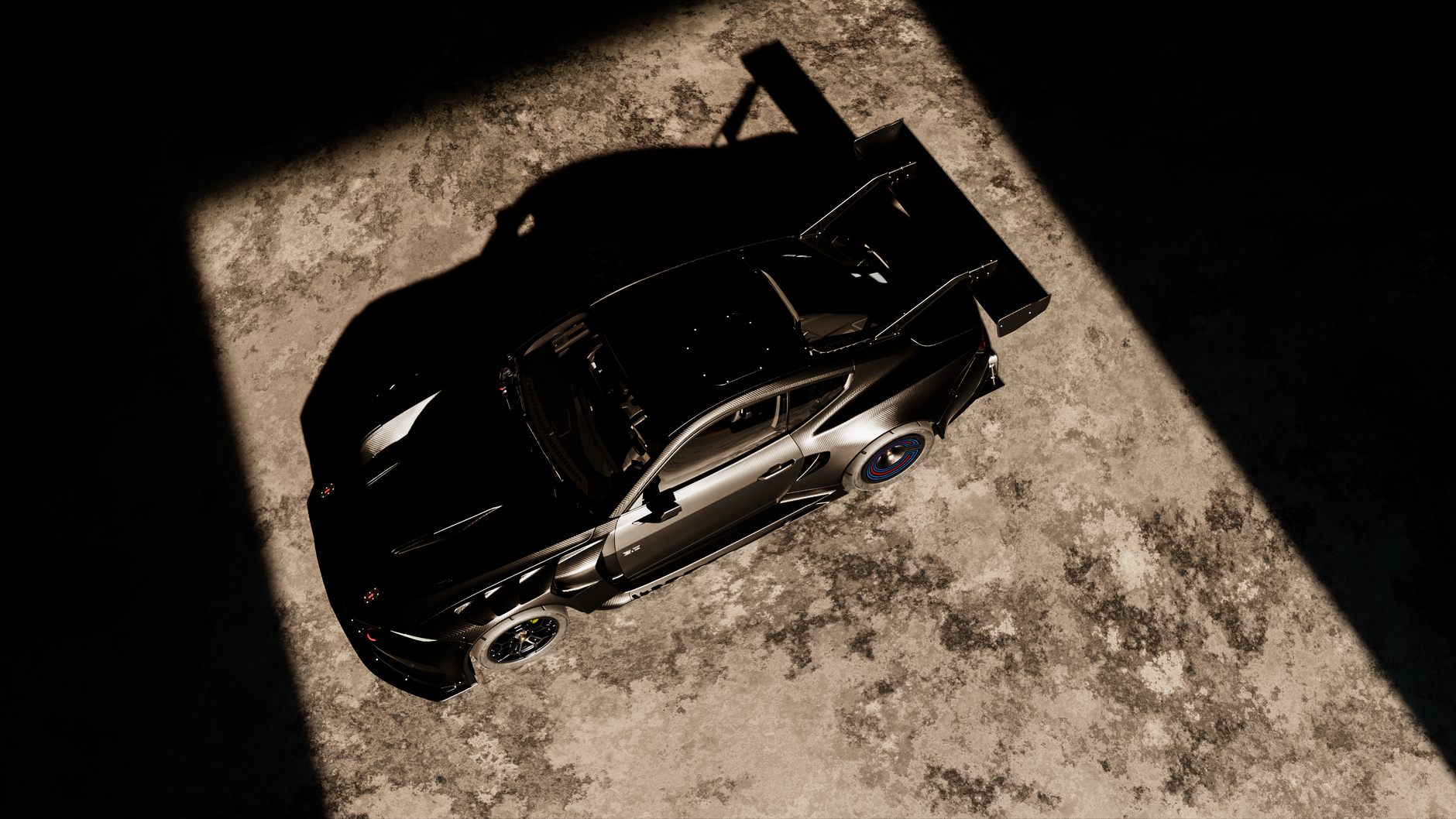 A sleek black sports car viewed from above in dramatic lighting casting shadows.