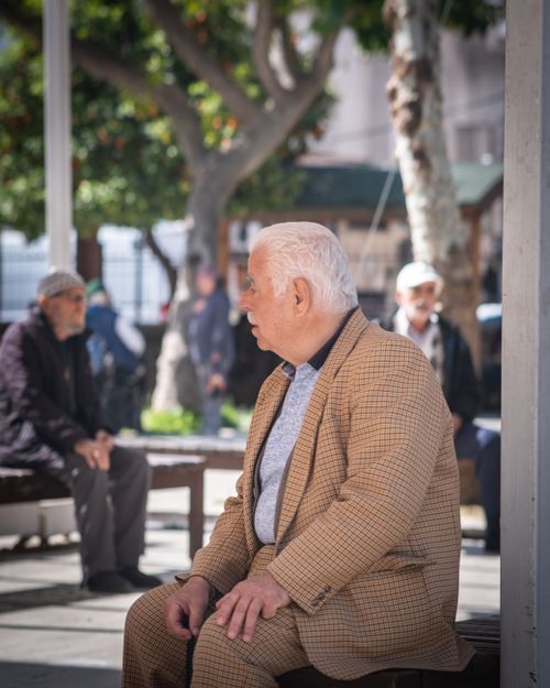 Free Senior adults sitting and socializing in an outdoor urban park setting on a sunny day. Stock Photo