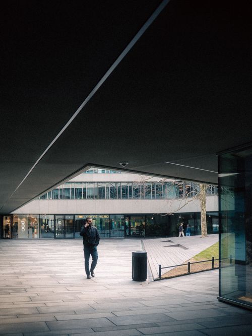 Free A person walks under a modern architectural structure in an urban setting. Stock Photo