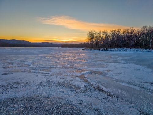 Free A peaceful winter sunrise casts warm light over a frozen lake in West Newton, Minnesota. Stock Photo