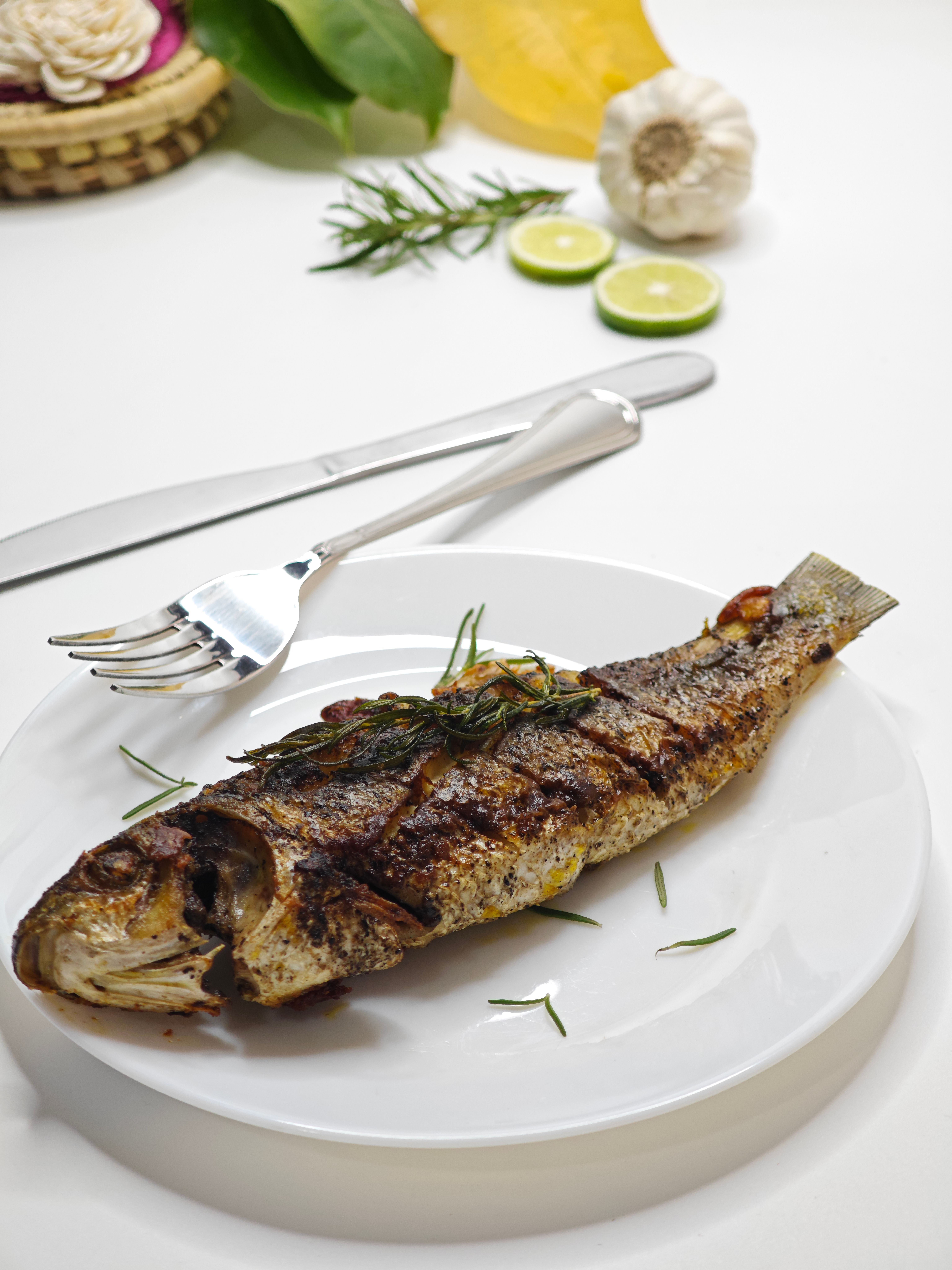 Delicious grilled fish served with fresh herbs and lime slices, perfect for a gourmet meal.