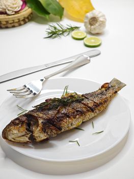 Delicious grilled fish served with fresh herbs and lime slices, perfect for a gourmet meal.
