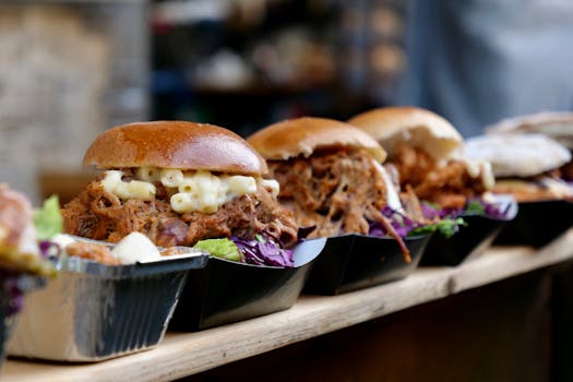 Tasty pulled pork sandwiches topped with creamy macaroni in a London market setting.