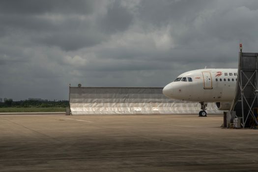 Wide view of a commercial jetliner stationed on a cloudy day at an airport's runway.