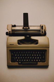 Old beige typewriter with Cyrillic keyboard on a neutral background, top view.