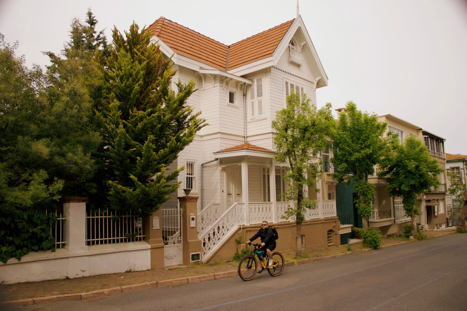 Charming Victorian-style house with cyclist passing by in Heybeliada, İstanbul, Türkiye.