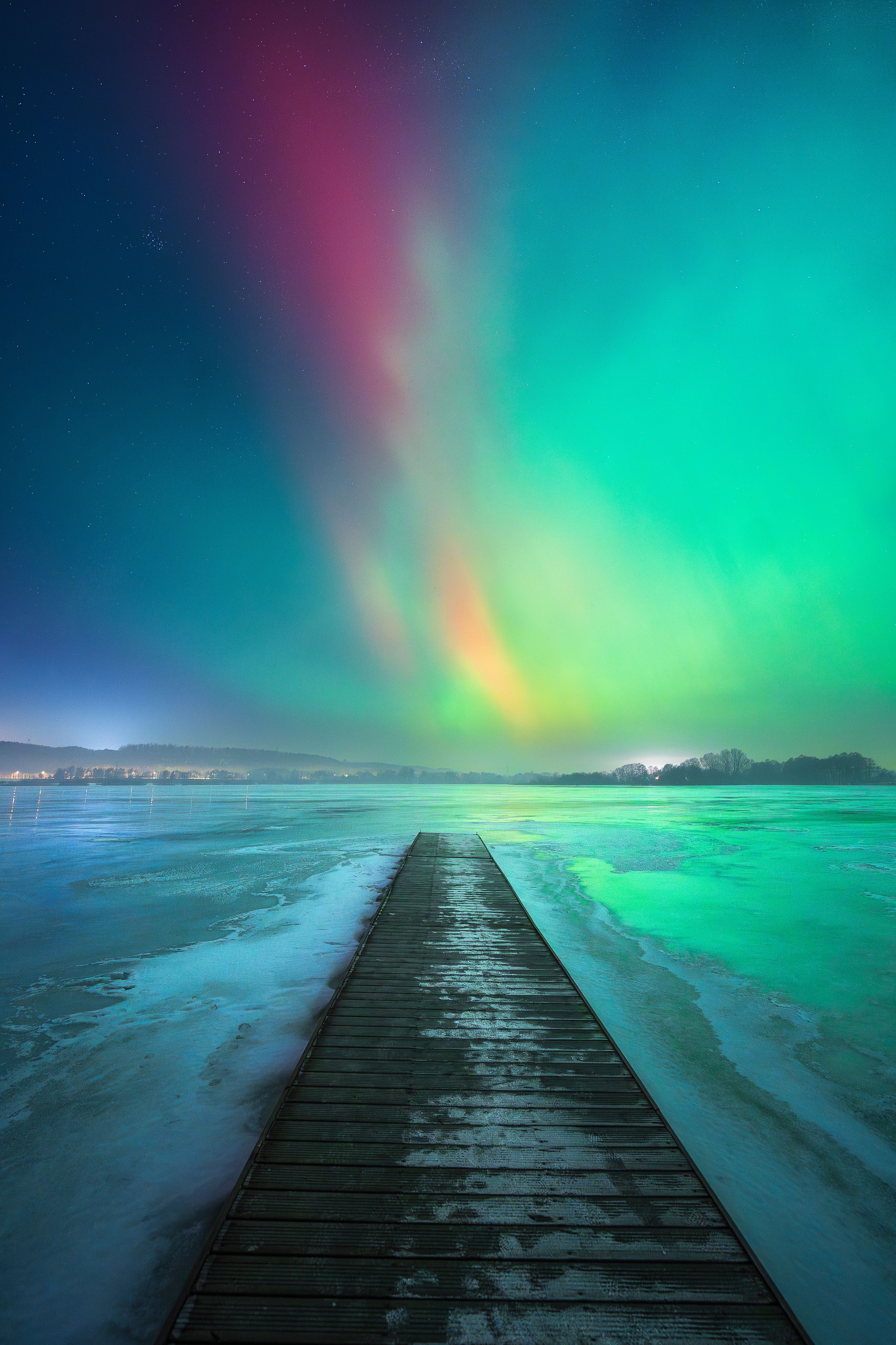 Captivating aurora borealis over a frozen lake in Poland captures nature's breathtaking winter beauty.