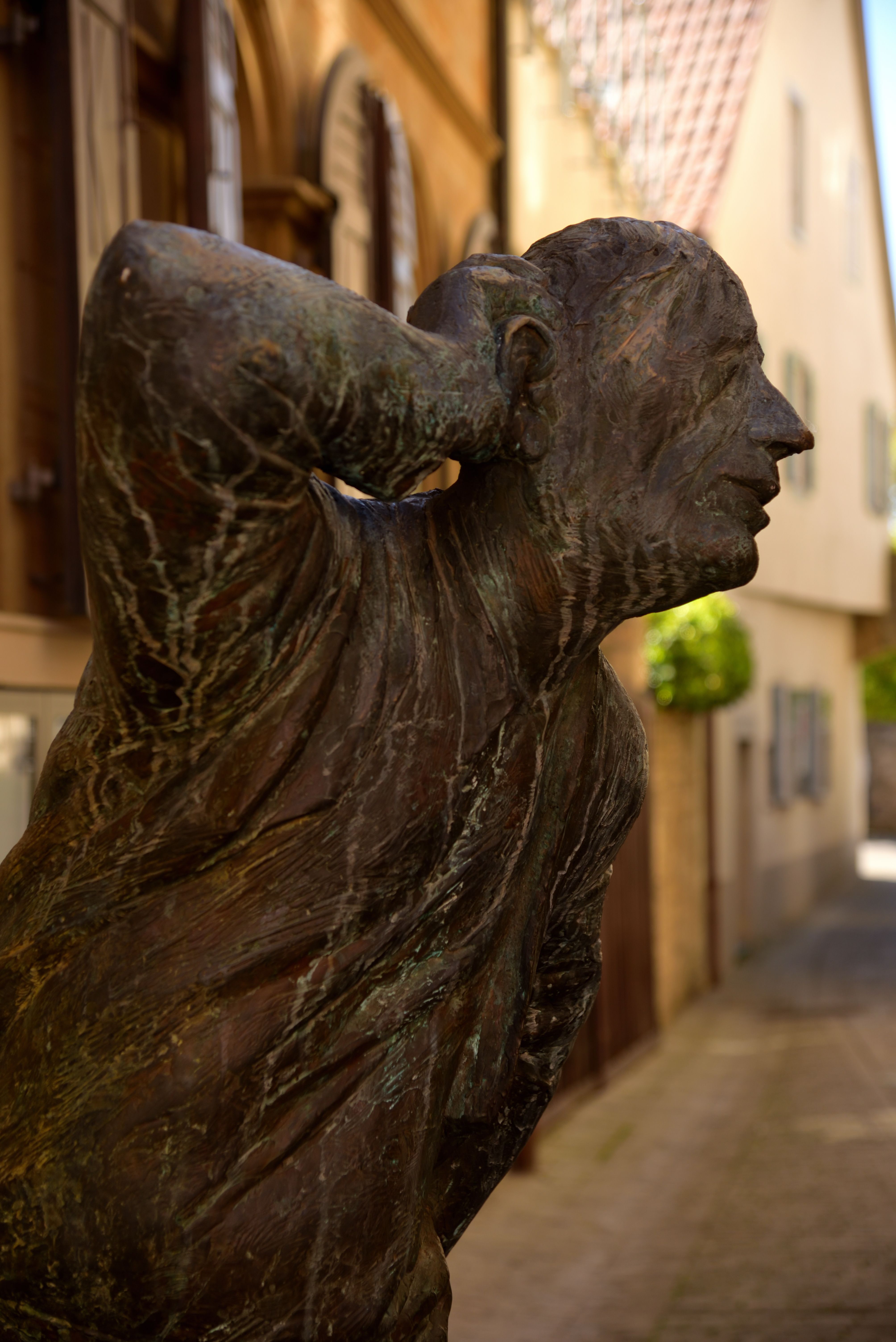 A bronze sculpture in an alleyway in Marktbreit, Germany, captured on a sunny day.