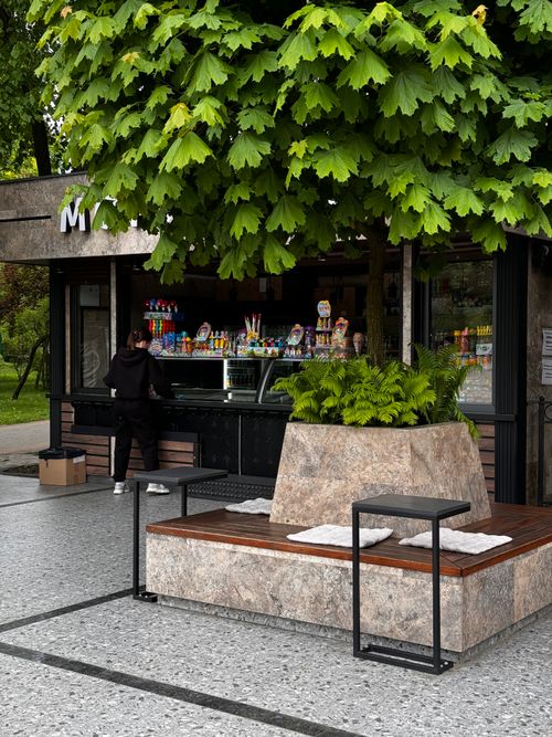 Free Contemporary outdoor kiosk offering snacks and drinks, situated under lush green trees in a park. Stock Photo