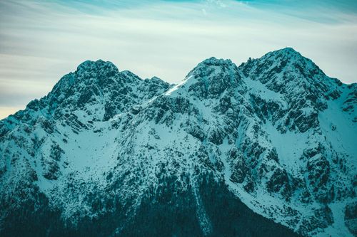 Free A stunning view of snow-covered mountain peaks against a serene sky, showcasing winter's beauty. Stock Photo