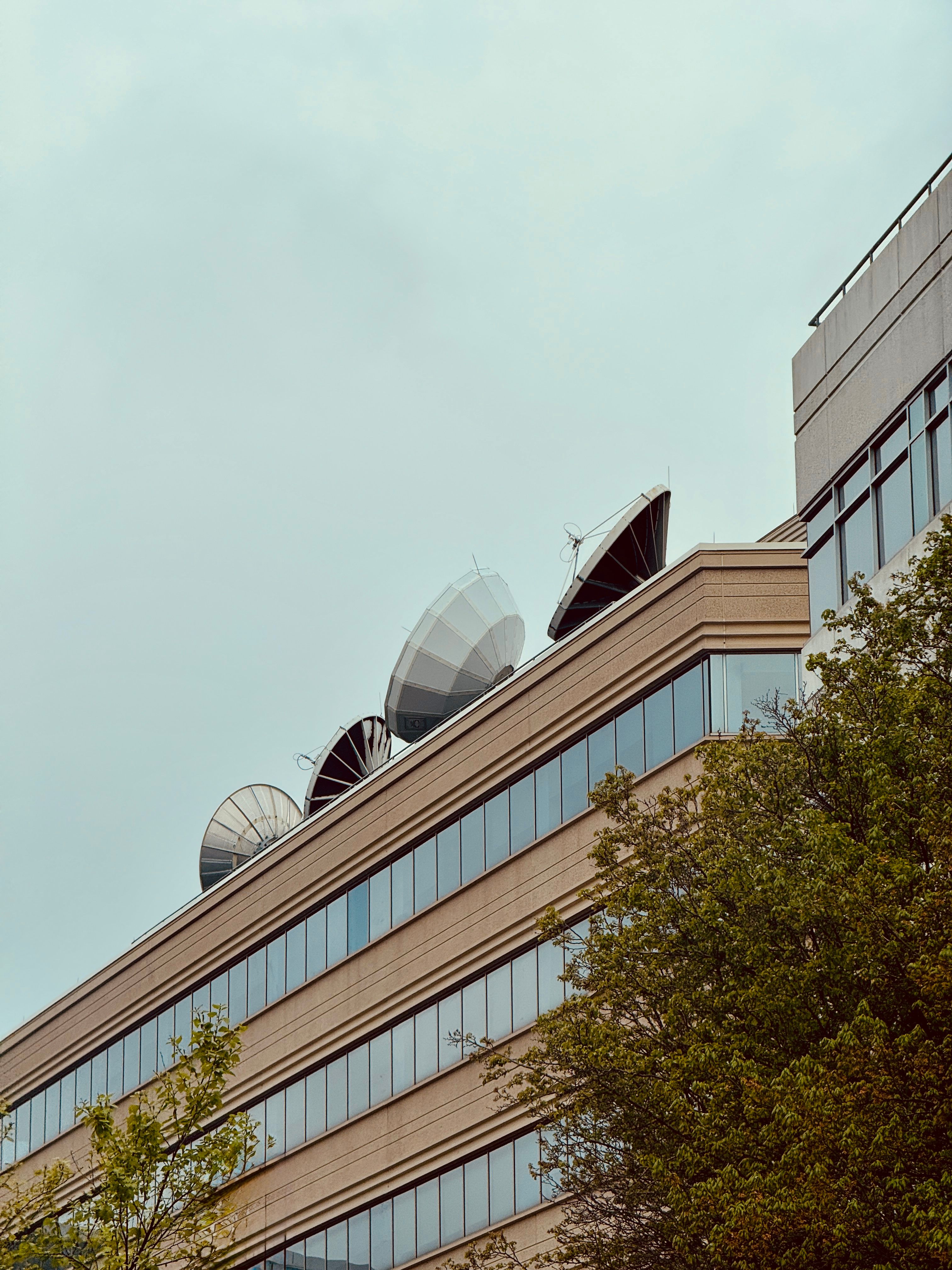 A contemporary building with satellite dishes against a clear sky in Boston, MA.