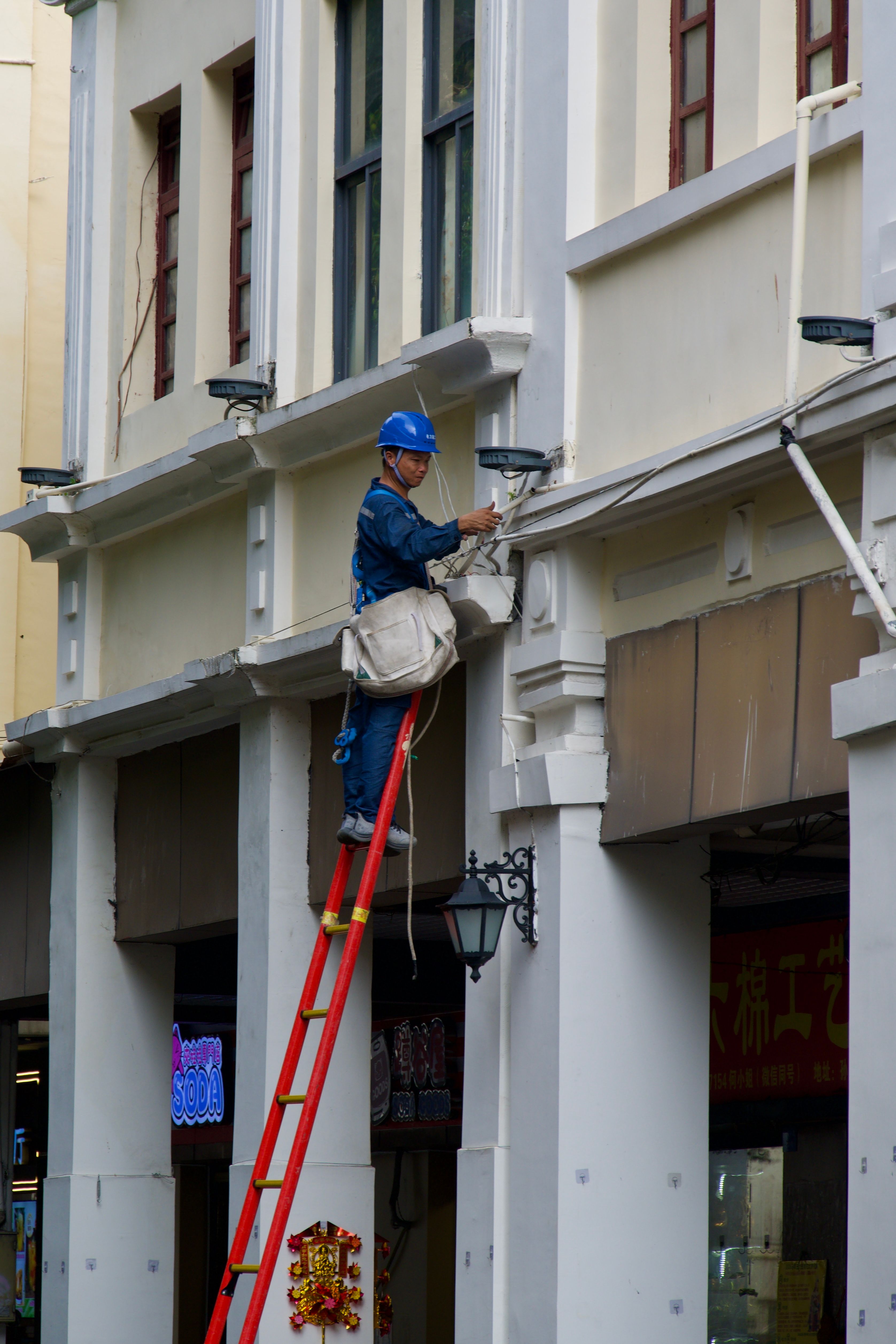 Construction Worker on Ladder Fixing Building Facade · Free Stock Photo